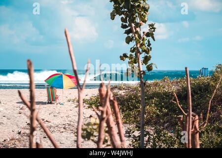 Beautiful shot of a beach with a colorful parasol and a beach chair with amazing waves Stock Photo