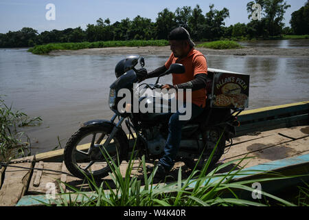 Libertad, Chiapas, Mexico. 23rd July, 2019. A pizza delivery man crosses from Los Limones, Guatemala to Libertad, Mexico on Tuesday. As the US has pressured Mexican authorities to crack down on migrants crossing the country to reach the U.S., such crossings have moved to sleepy areas like Libertad, where there is little or no official Mexican border security. Credit: Miguel Juarez Lugo/ZUMA Wire/Alamy Live News