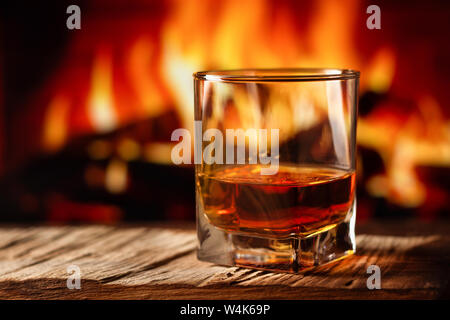 Whiskey in a glass with fire in the fireplace on the background Stock Photo