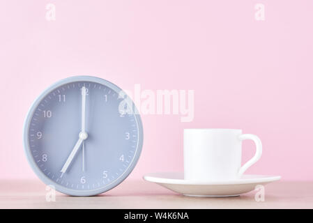 Classic gray alarm clock and white coffee cup on pink background Stock Photo