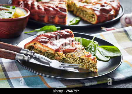 close-up of a slice of Spinach Ricotta pie served on a black plate with sliced pie at the background, horizontal view from above Stock Photo