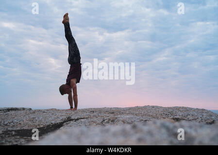 Fit man doing a hand stand during yoga practice outside Stock Photo