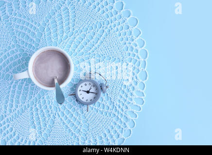 Morning cup of coffee and an alarm clock on a light blue background. Top view. Space for your text. Stock Photo