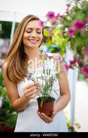 Happy woman shopping beautiful flowers in garden center Stock Photo