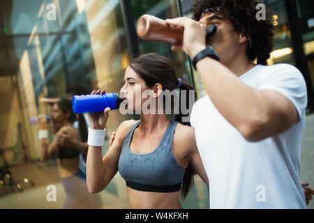Young man and woman having break after running workout and drinking water Stock Photo