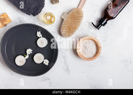 Spa still life with different body and skin care essentials and bowl with floating candles, top view Stock Photo