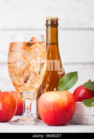 Bottle and glass of homemade organic apple cider with fresh apples in box on wooden background, Glass with ice cubes Stock Photo