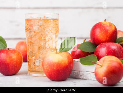 Glass of homemade organic apple cider with fresh apples in box on wooden background, Glass with ice cubes Stock Photo