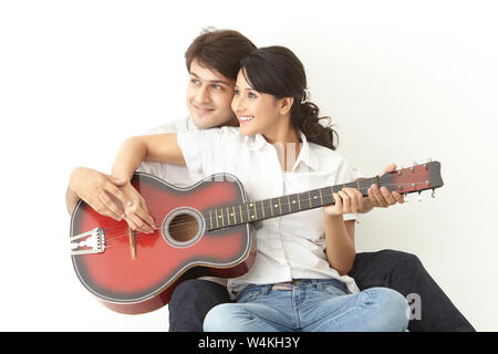 Man teaching woman to play guitar Stock Photo