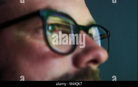 Berlin, Germany. 16th July, 2019. A man's glasses reflect the green zeros and ones of a screen. Credit: Annette Riedl/dpa-Zentralbild/dpa/Alamy Live News Stock Photo