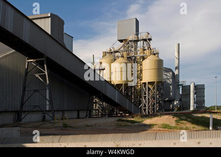 Mining, managing & transport of titanium mineral sands. Rear of warehouse & storage silos containing mineral products plus start of conveyor to port. Stock Photo