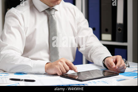 Businessman working with tablet pc, calculating, reading and writing reports. Office employee, table closeup. Business financial accounting concept. Stock Photo