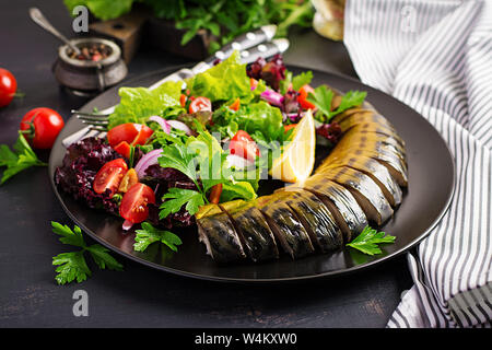 Smoked mackerel and fresh salad on dark background. Stock Photo