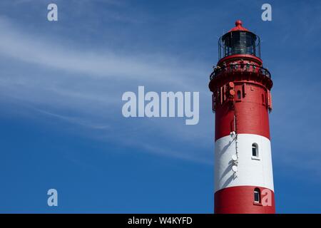 Beautiful wide shot of the top of a red and white lighthouse tower on a sunny day at the beach Stock Photo