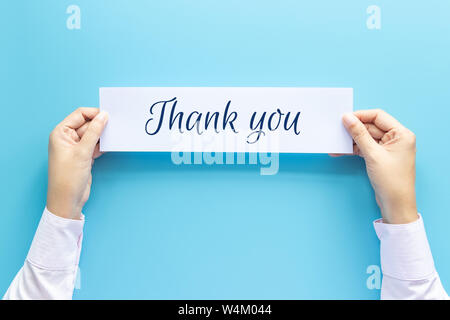 woman hand holding card with the word thank you isolated on blue background, studio shot Stock Photo