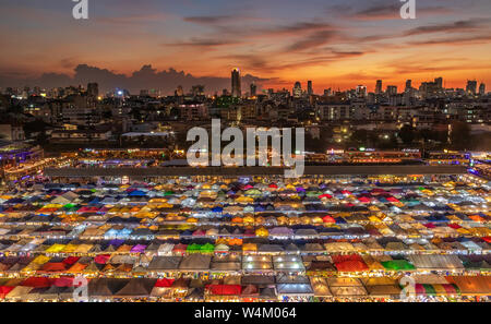 top view of busy Asian street food at railway night market in Thailand with colorful stall and light at night time Stock Photo