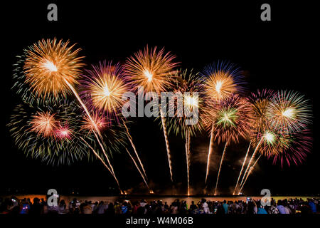 cheering crowd watching colorful fireworks and celebrating on the beach during festival Stock Photo
