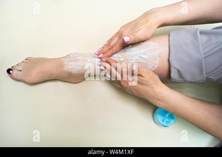 Rejuvenation procedure. The girl puts a blue scrub on her leg Stock Photo