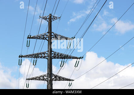 High voltage towers with electrical wires on blue sky and white clouds background. Electricity transmission lines, power supply concept Stock Photo