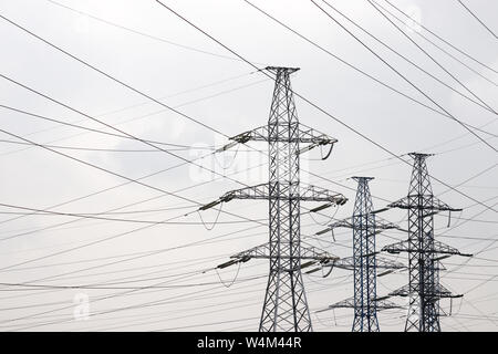 High voltage tower with electrical wires on cloudy sky background. Electricity transmission lines, electric power station Stock Photo