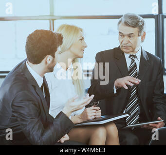 A group of businessmen discussing the policies of the company using a tablet computer in a modern office Stock Photo