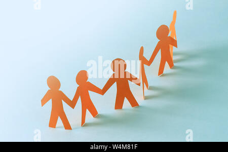 Team Paper doll people holding hands in a backlight Stock Photo