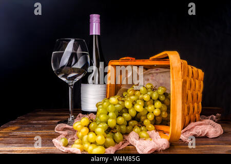 Picture of empty wine glass, grapes of green on wooden basket on table Stock Photo