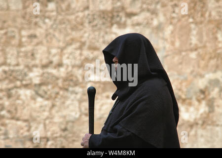 Hooded spooky looking medieval monk in a traditional black robe with staff Stock Photo