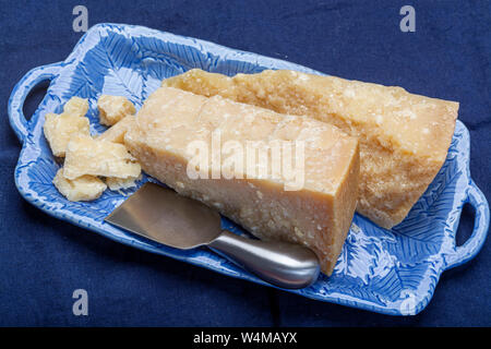 Cheese collection, Italian original aged Parmesan cheese in two pieces served on blue board with knife close up Stock Photo
