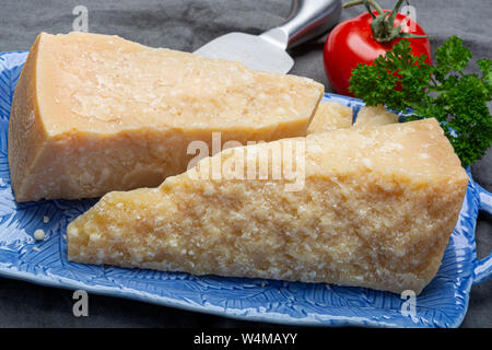 Cheese collection, Italian original aged Parmesan cheese in two pieces served on blue board with knife close up Stock Photo