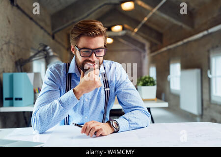 Handsome architect looking on blueprints at modern office Stock Photo