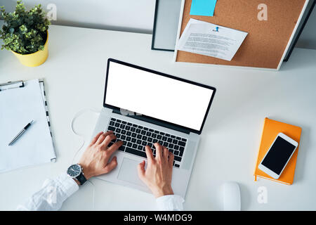Overhead view of man working on laptop in modern office Stock Photo