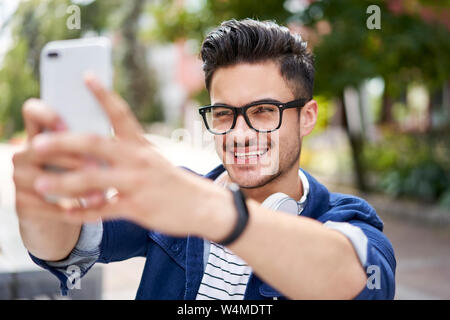 Cheerful male student taking selfie outdoors on campus grounds Stock Photo