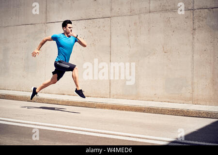 Health and fitness concept. Man doing sprinting and jumping exercises during workout session in the city Stock Photo
