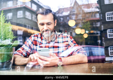 Man using smartphone while sitting in cafe during winter time Stock Photo
