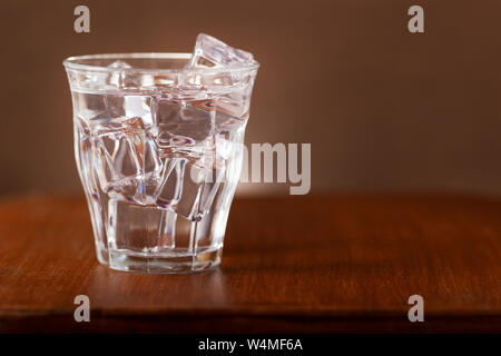 Nostalgia still of a glass of fresh water with ice cubes on  a wooden table Stock Photo