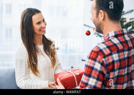 Portrait of cute couple exchanging presents during christmas. Happy family celebrating Stock Photo