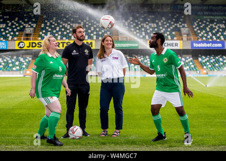 Ahemd Elneel (right), captain of the Northern Ireland homeless football team, and who is originally from Sudan heads the ball to Northern Ireland's homeless woman's player, Janette Kelly (left), as Justin McMinn (second from left) of Street Soccer NI, and Katherine Hill (second from right), Director of Active Communities at the Department for Communities watch on, during a photocall at The National Stadium, Windsor Park, ahead of the teams departure tomorrow for the Homeless World Cup in Cardiff this coming weekend. Stock Photo