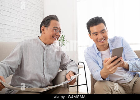 Happy father and son use cellular phones Stock Photo