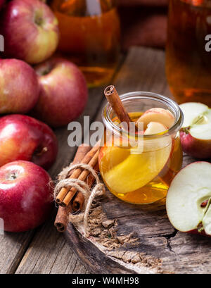 Glass of apple juice with sliced apples and cinnamon sticks on a rustic wood surface Stock Photo