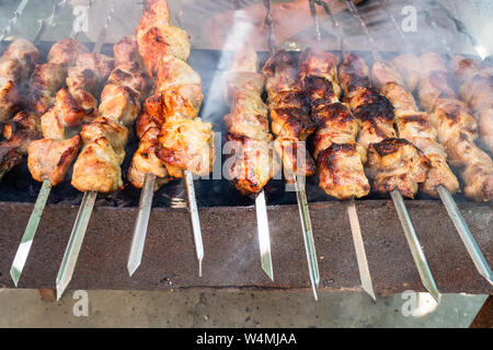 man cooks pork shish kebabs (shashlyk) on brazier outdoors Stock Photo