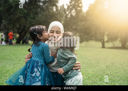 two little girl kissing her mother Stock Photo