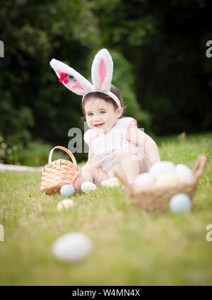 1-year-old toddler in Easter Bunny costume collecting eggs outside Stock Photo