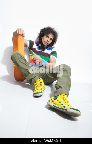 Man holding skateboard and showing peace sign Stock Photo