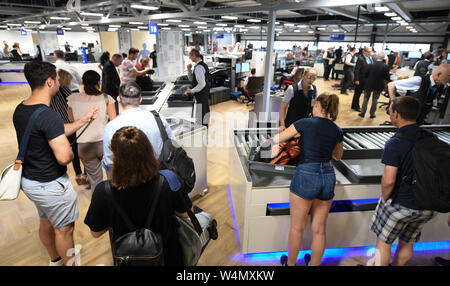 24 July 2019, Hessen, Frankfurt/Main: Air passengers are standing at a passenger checkpoint in a newly constructed hangar in Terminal 1 at Frankfurt Airport. The seven new control lanes are intended to ensure smoother operation. Thanks to a new configuration, more passengers per hour can be guided through than with the technology previously used. Photo: Arne Dedert/dpa Stock Photo