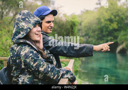 Couple on a eco tourism during winter. Man pointing something on the forest and the woman with an surprised expression. Focus on the man. Bonito MS, B Stock Photo