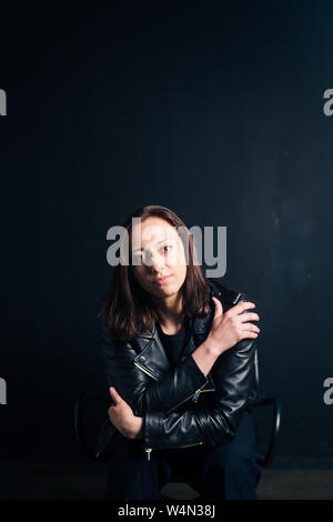 Studio portrait of an attractive young woman in a black leather jacket against a plain background Stock Photo