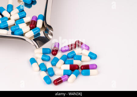 Colorful antibiotic capsules on stainless steel drug tray and fall on white background Stock Photo