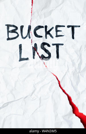 Phrase 'bucket list' handwritten on crumpled torn paper, top view. Sign, concept of failed plans or hopes, abstract illustrative image Stock Photo