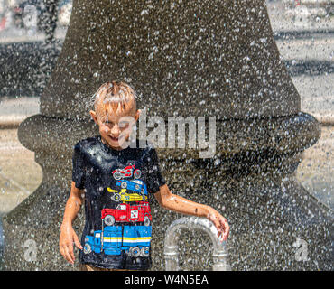 24 July 2019, Hessen, Frankfurt/Main: The six-year-old Artem stands in the summer heat under the fountain at the Alte Oper and is showered off by the cool water. Photo: Frank Rumpenhorst/dpa Stock Photo